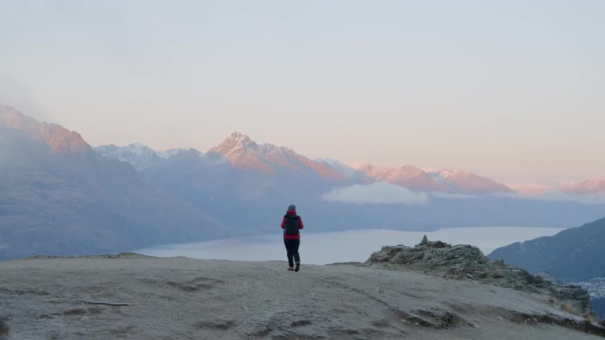 The woman hikes on the hill by the lake
