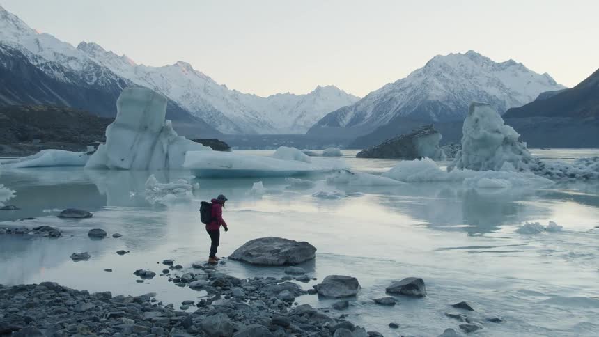 A person walking on rocks next to a small river