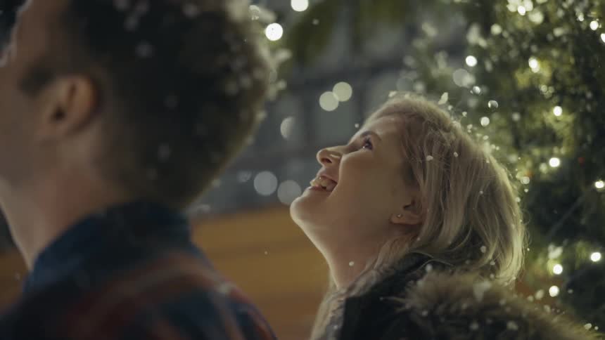 A man and woman stand outside in the snow