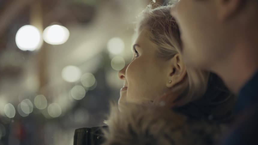 Man and woman standing outdoors looking at snow falling