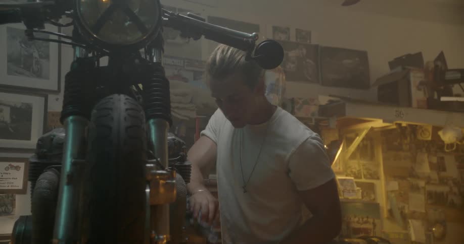 Man wiping his forehead while working on his motorcycle