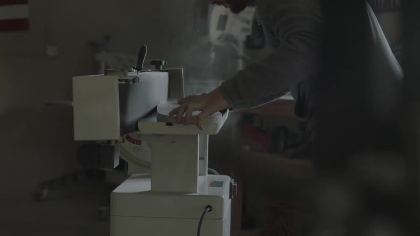 Man using a belt sander on a piece of wood