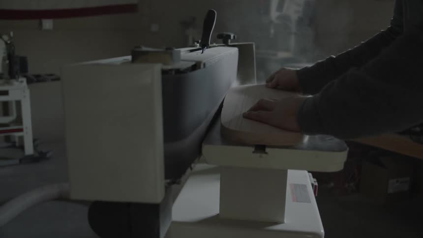 A man uses a belt sander to sand wood