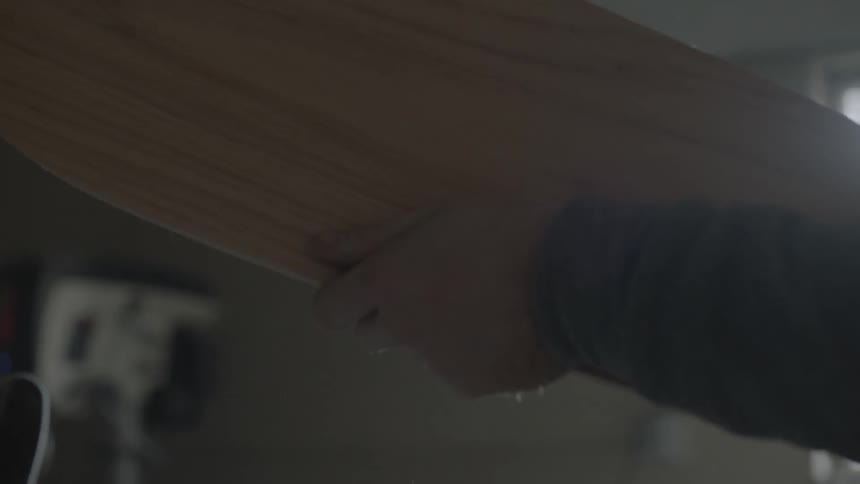 A man tests the smoothness of a wooden board