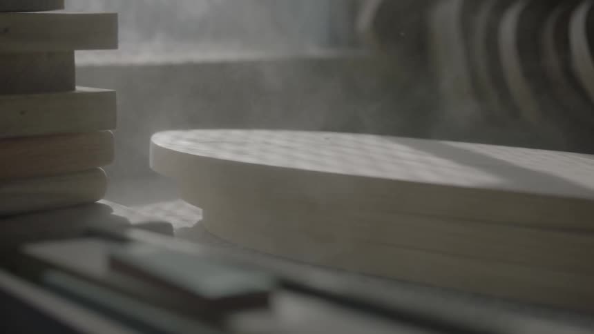 A person lays down a stack of wood on a desk