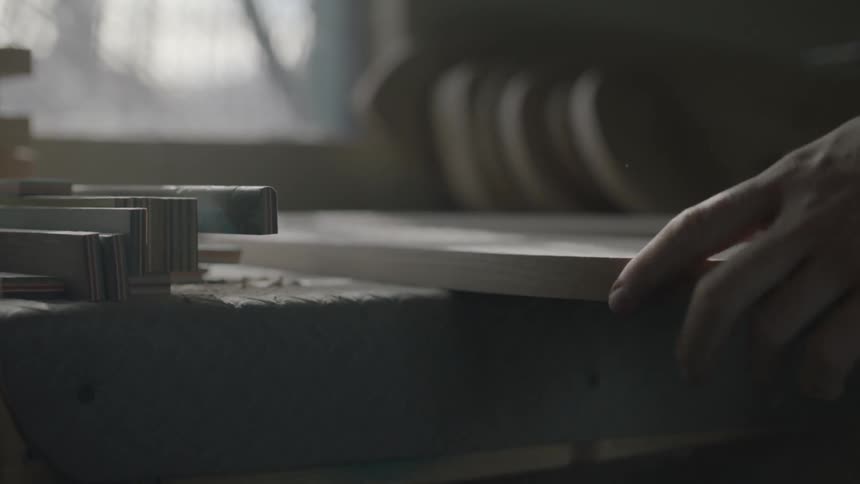 A man places a piece of wood on a workbench