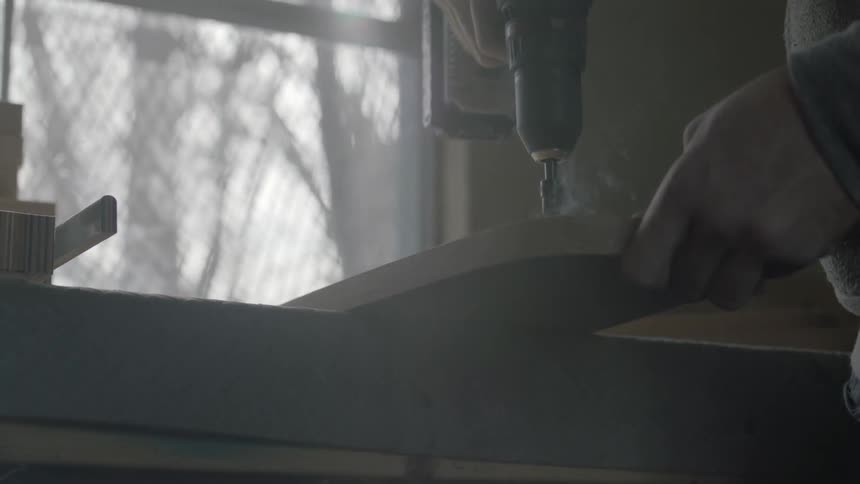 Man drilling a hole through a piece of wood