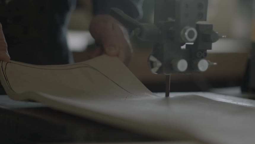 A man uses a table saw to cut a curved piece of wood