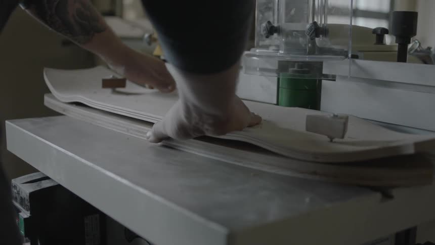 A man smooths the side of a piece of wood