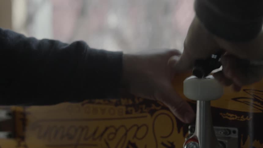 Man tightening  the wheel of a skateboard