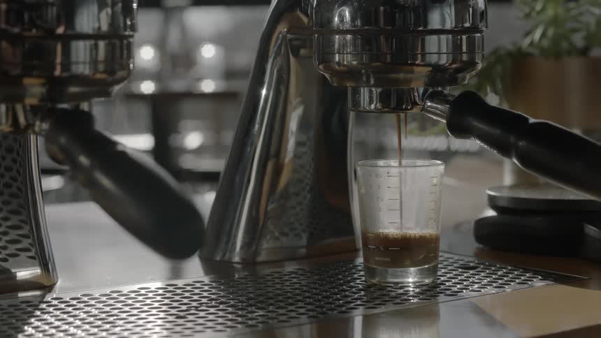 A machine brewing a drink into a clear glass slowly