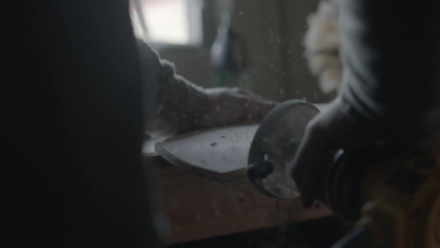 A man is using a belt sander on a piece of wood
