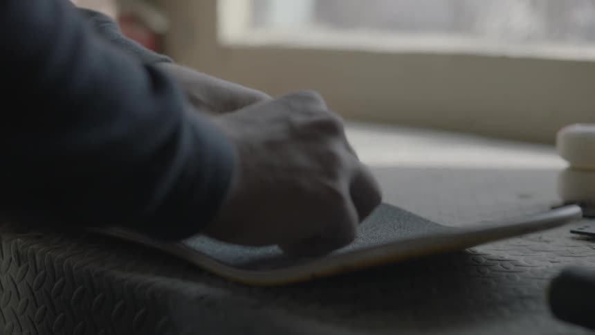 A man setting screws into holes drilled into a skateboard deck