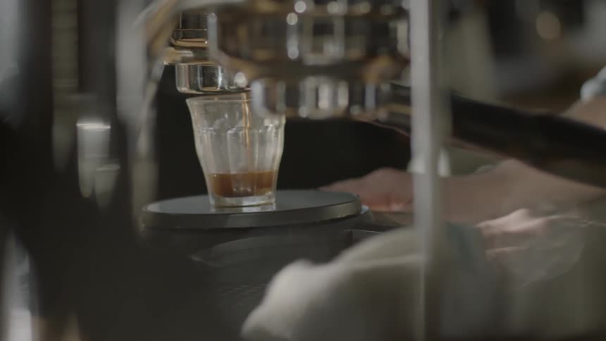 A beverage drips into a glass cup