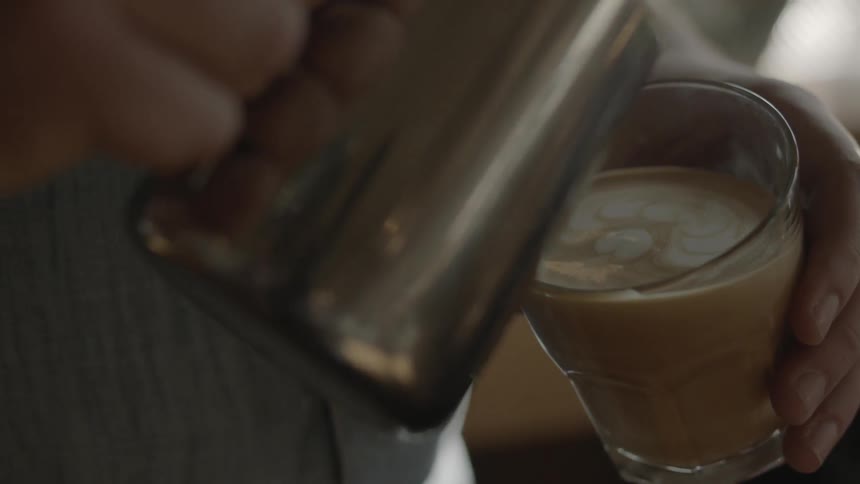 Someone is pouring milk into a cup of coffee