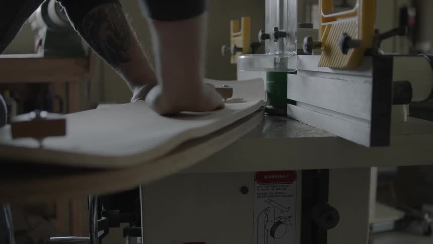 A man using a table sander to sand and shape a piece of wood