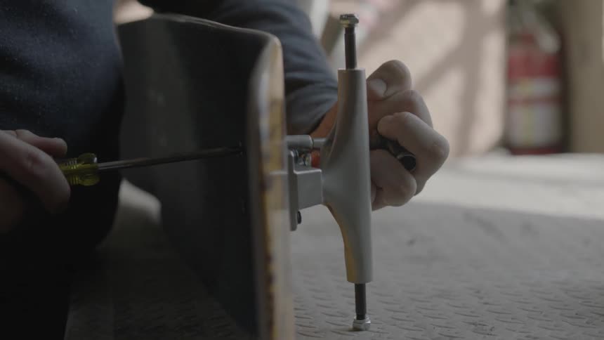 A man using a screwdriver and socket to tighten screws on a skateboard