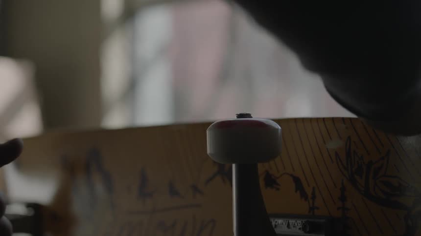 A man using an allen wrench to tighten the wheels on a skateboard