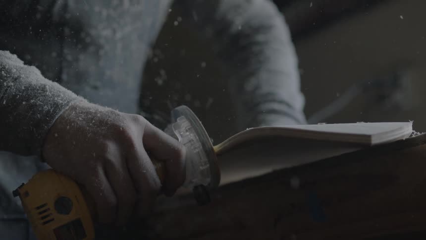A man sands the edges of a piece of wood