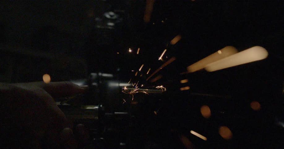 A cnc machine grinds a piece of metal as sparks fly away from it