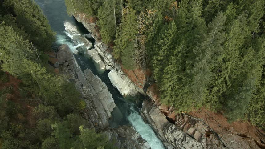 View of a river rushing between tree-lined cliffs and into a lake