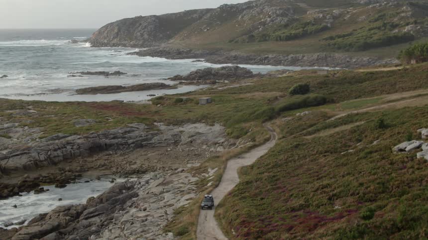 Car moves along road between beach and hillside
