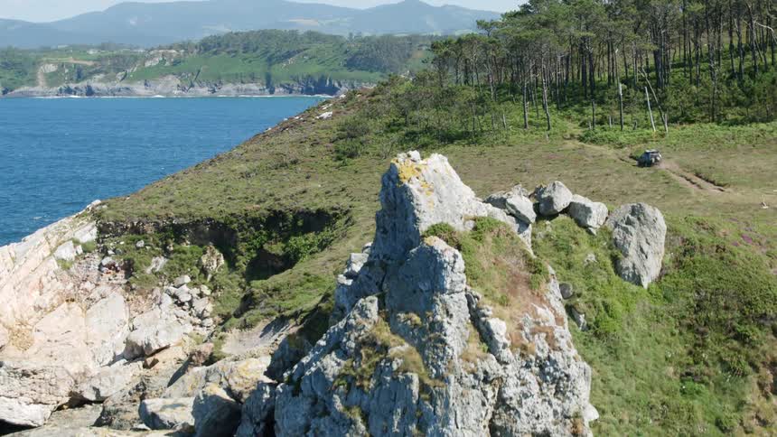 Some large rocks that are on the side of a cliff overlooking water
