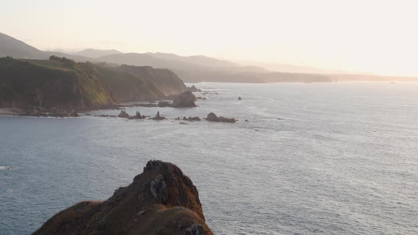 Pan over a mountain region overlooking the sea on a bright and sunny day