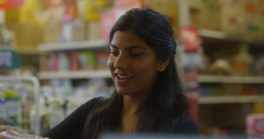 Woman reaching the grocery counter and talking to the clerk