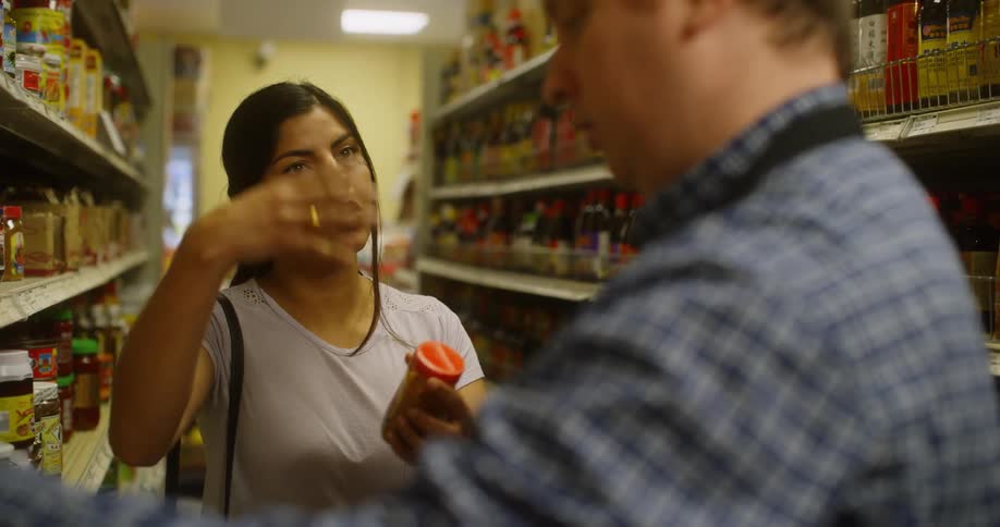 Woman in a grocery aisle talking with a grocery worker
