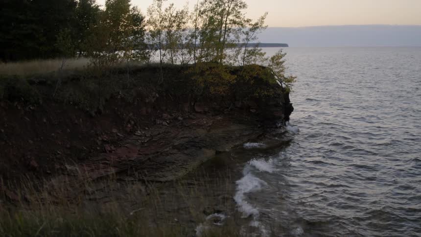 Waves of murky water crash against a rocky shoreline