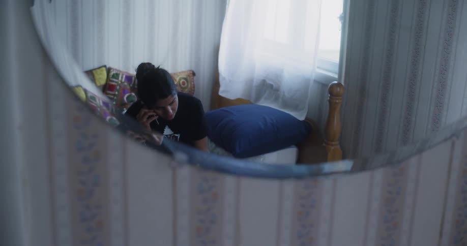 A young woman uses a phone in the bedroom