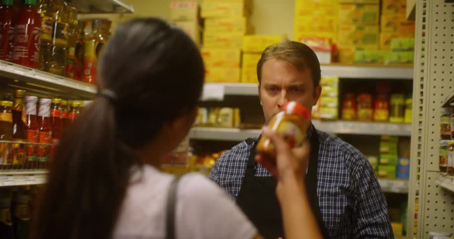 Woman in a grocery aisle asking the help of a grocery worker