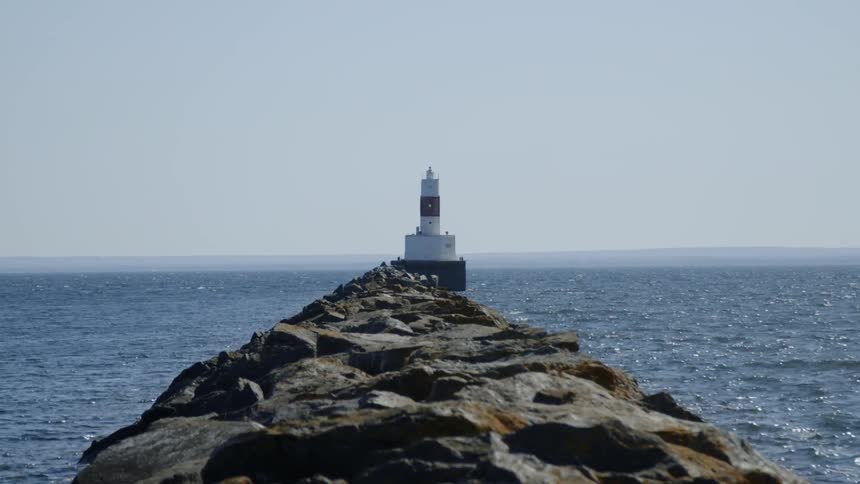 Lighthouse at the end of a rocky ledge overlooking the ocean