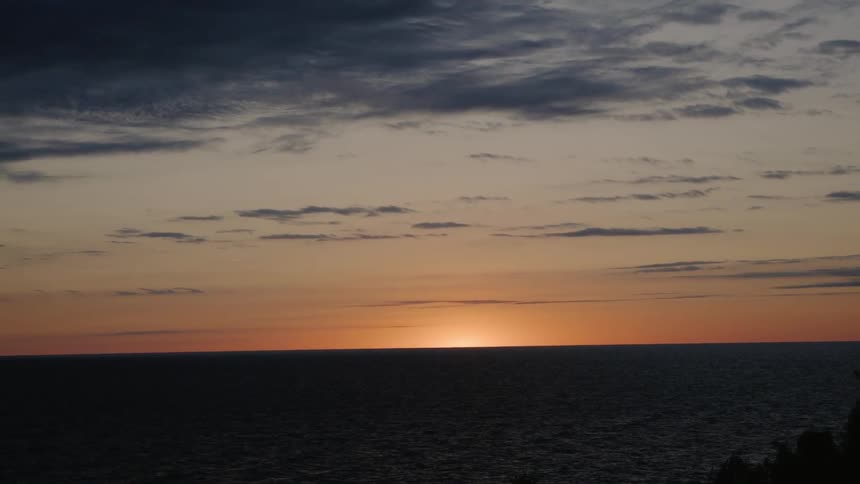 The sun sets behind the ocean