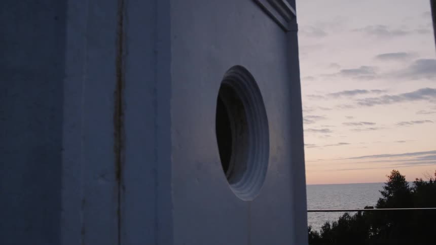 A building with a round hole for a window stands above a body of water