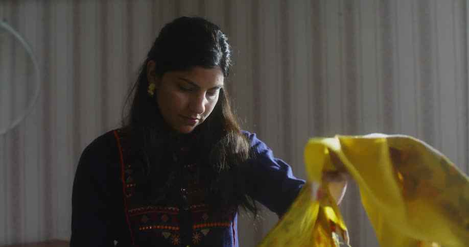 A woman folds a yellow dress