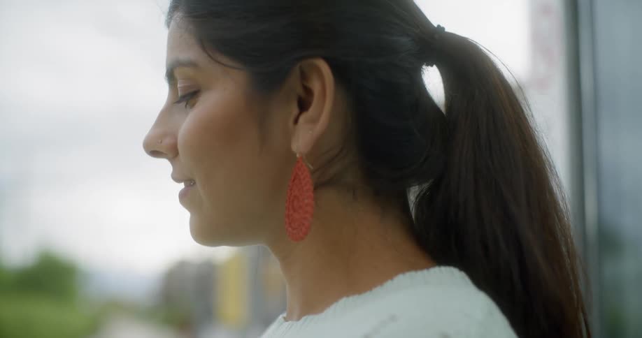 A woman with red earrings stands looking over at something