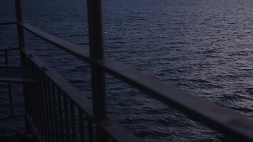 The ocean ripples in the wind under a metal dock