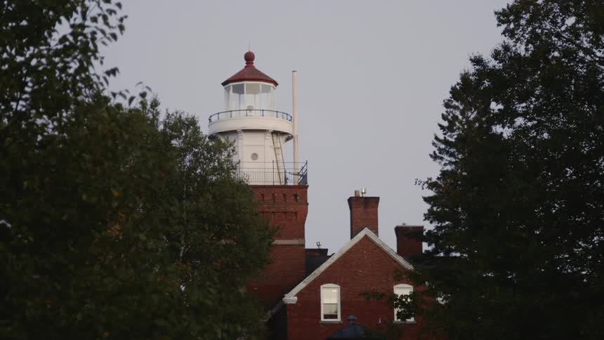 Lighthouse surrounded by trees blinks once