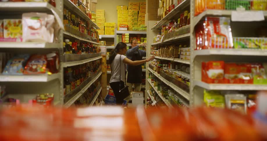 Woman asking the help of a grocery store worker in a grocery aisle