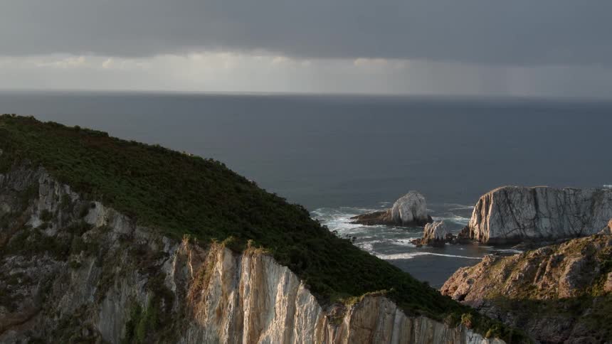 The ocean waves flow towards the cliff shore