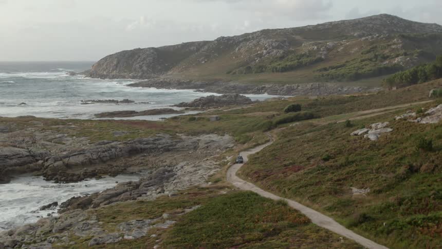 We move along a road by the ocean as one car moves along it