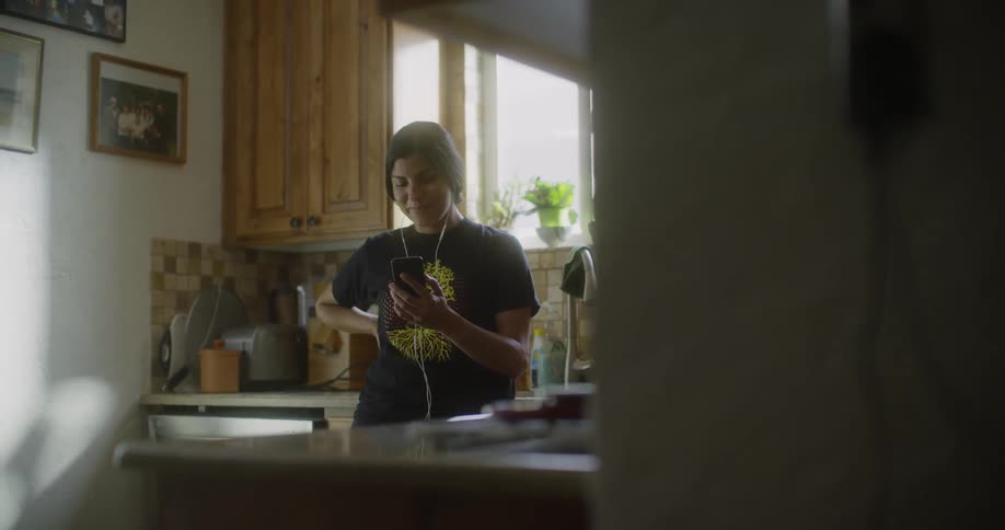 Woman smiling with earphones looking at her phone