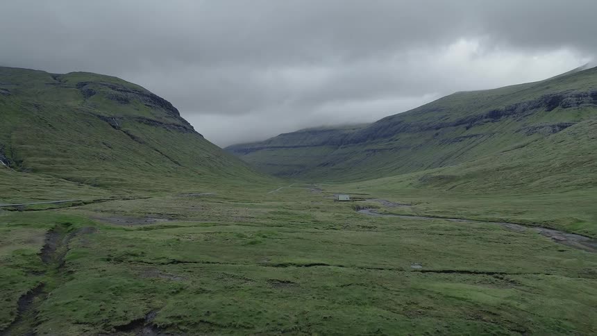 Birds fly over winding streams that flow through a valley