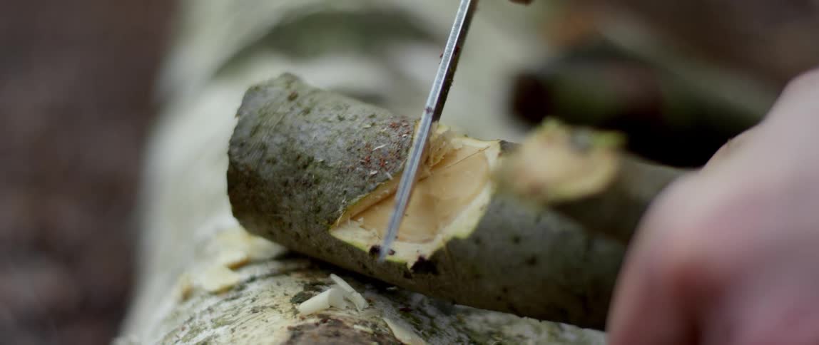 A person carves a piece of wood with a knife