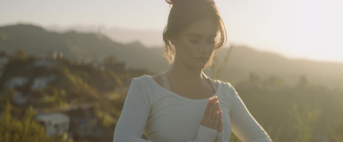 Woman practices yoga as she stands outdoors
