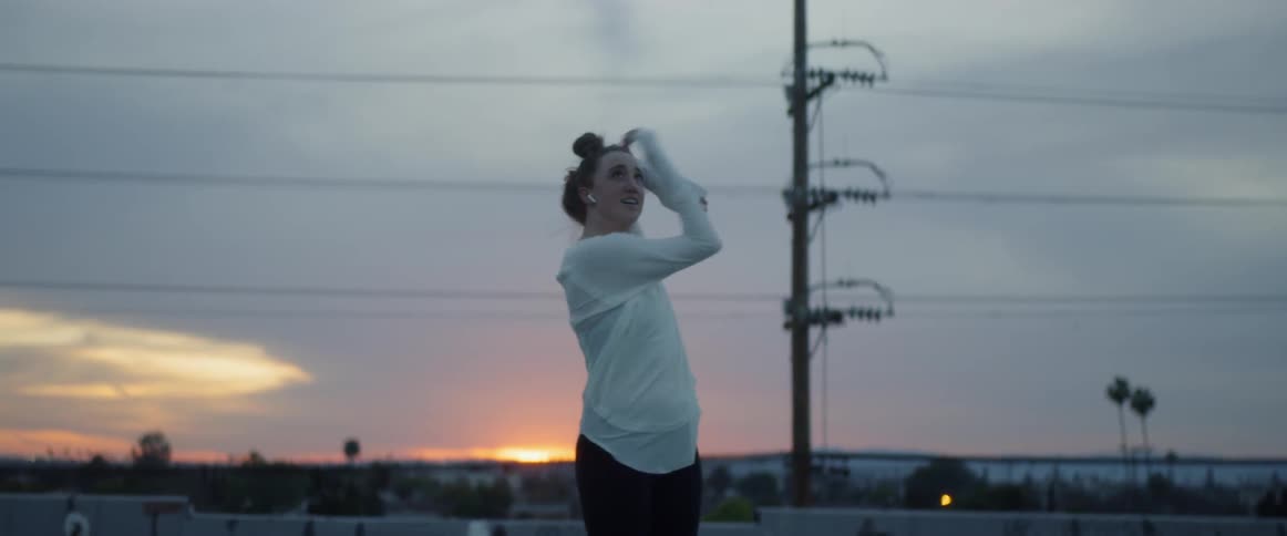 Woman wearing earphones dancing on a city rooftop