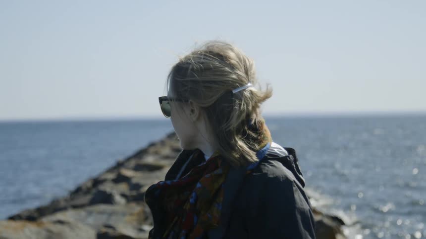 A woman looks out across the ocean on a cold winter day