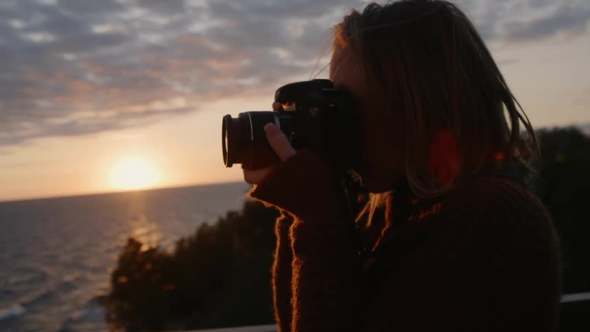 A woman takes photographs on the shore